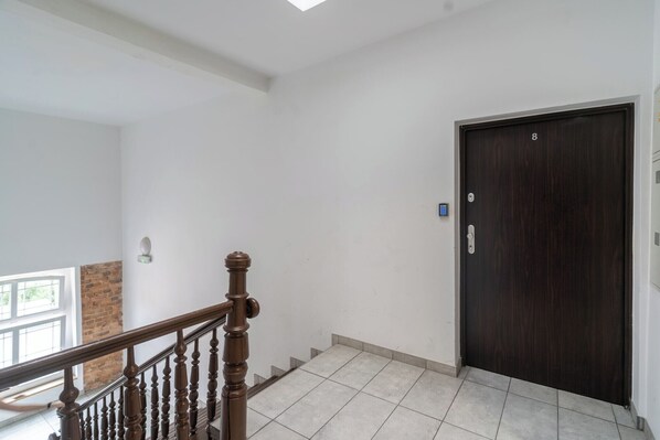 A staircase with a wooden handrail leading to a dark wooden door with a keypad lock.