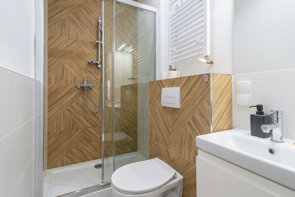 A modern bathroom with a shower, toilet, and sink.
