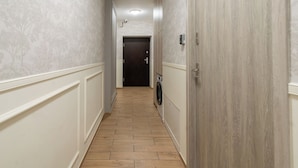 Un couloir avec un papier peint à motifs, un plancher en bois et une porte au fond.