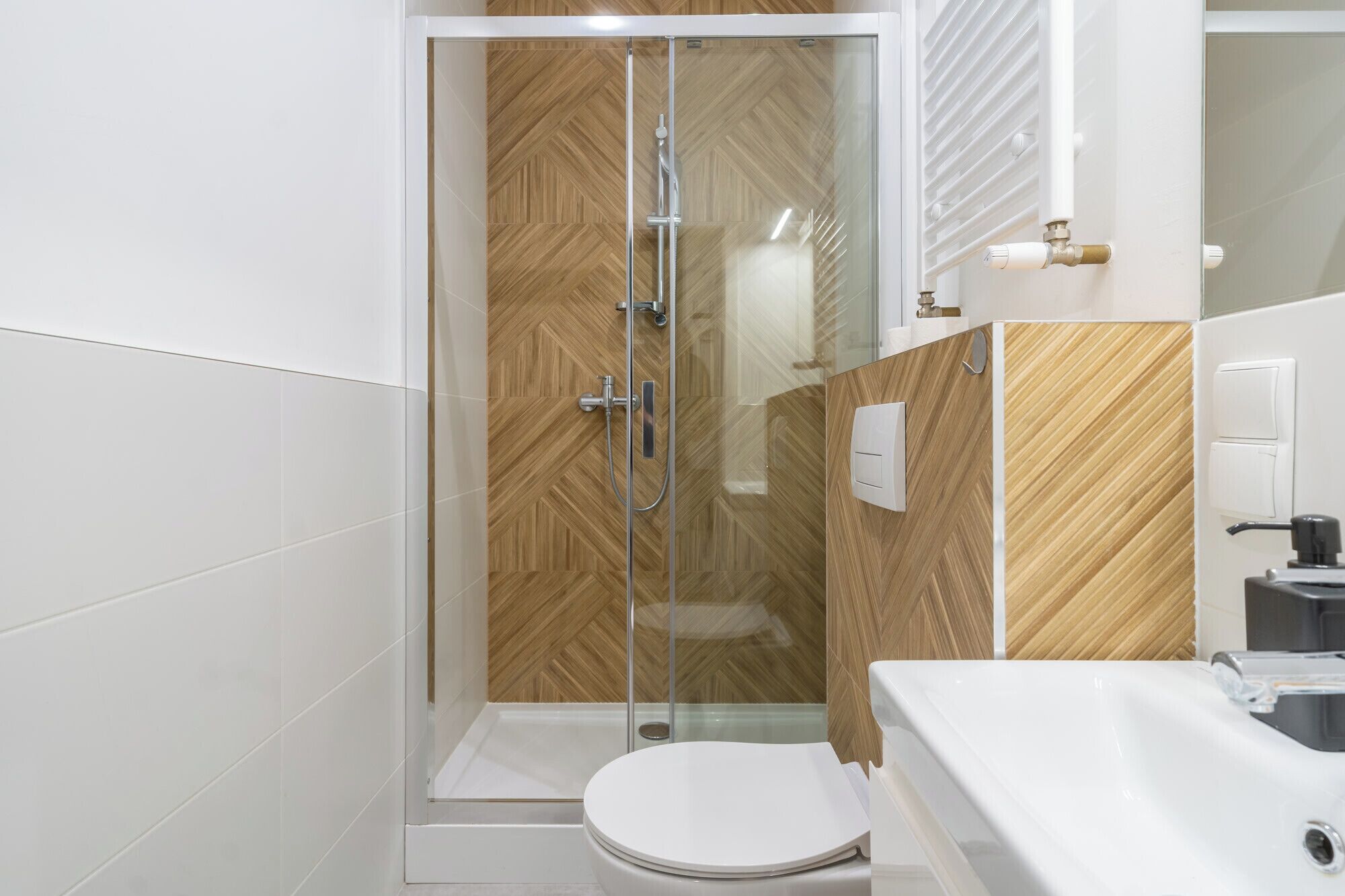 A modern bathroom with a glass-enclosed shower, a white toilet, and a white sink.
