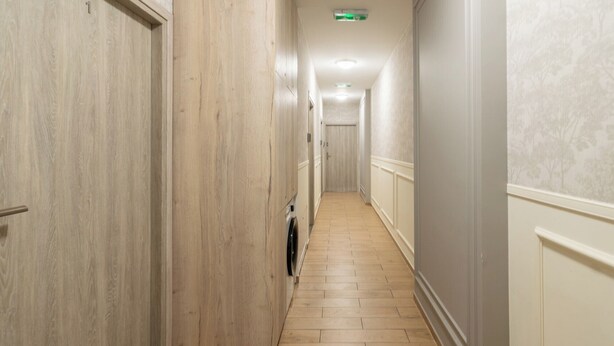 A hallway with wooden paneling on the walls, a tiled floor, and a door at the end.