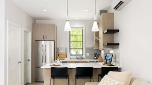 Una cocina moderna con una isla central, electrodomésticos de acero inoxidable e iluminación colgante.