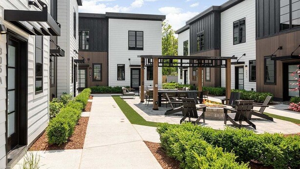 A modern outdoor patio area with a pergola, seating, and a fire pit.