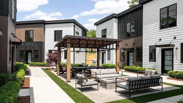 Un patio con mobiliario exterior, una pérgola y un césped cuidado.