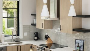 Une cuisine moderne dotée d’un îlot central, de tabourets de bar, d’une machine à café et de luminaires suspendus.