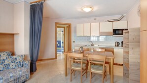 Un espacio habitable compacto con kitchenette, comedor y sofá.