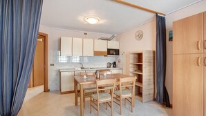 Una cocina compacta con una mesa de comedor, sillas, microondas y un armario de madera.