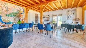 A spacious dining area with wooden beams, blue chairs, and a colorful mural.