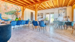 Un comedor amplio con vigas de madera, sillas azules y un mural colorido.