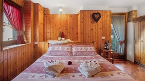 Una stanza con rivestimento in legno, un letto, un tavolino con bottiglie di vino e una decorazione a forma di cuore sulla parete.