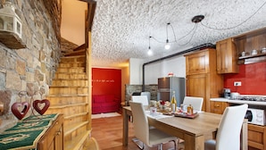 Una cucina accogliente con mobili in legno, un tavolo da pranzo e una parete rossa.