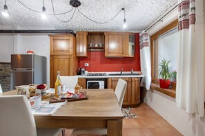 Uma cozinha com armários de madeira, uma mesa de jantar e uma janela com cortinas.