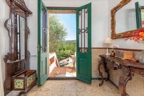An interior with a wooden door leading to a balcony, a mirror, and a table with a lamp and decorative items.