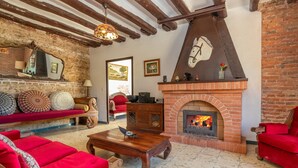 A cozy living room with a brick fireplace, red sofas, and a wooden coffee table.