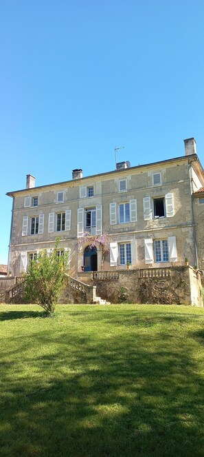 Un grand bâtiment en pierre doté de nombreuses fenêtres et d’une entrée centrale.