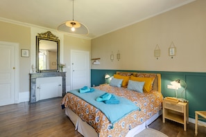 A bedroom with a bed, bedside tables, a mirror, and a dresser.