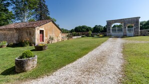 A rural property with a gravel path, a stone building, and a metal gate.
