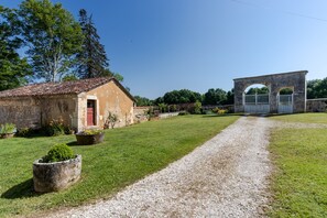 A rural property with a gravel path, a stone building, and a metal gate. - "Exotic" Room with Shared Terrace, Shared Garden, and Wi-Fi (Savignac-les-Églises)