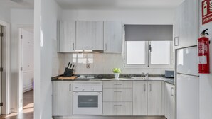 A modern kitchen with white cabinetry, a built-in oven, a sink, and a window above the countertop.