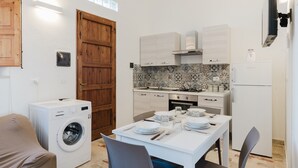 Cocina compacta con lavadora, mesa de comedor lista para cuatro personas y una puerta de madera grande.