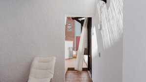A narrow hallway with a white chair, a tiled floor, and a view of a building with a brick wall and a window. - Apartment 'Sea Nest - Near the Beach' with Private Terrace, Wi-Fi and Air Conditioning (Balestrate)