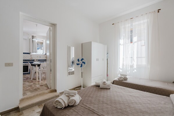 Una habitación de hotel con una cama, una mesita de noche, un espejo, un ventilador y vistas a la cocina.