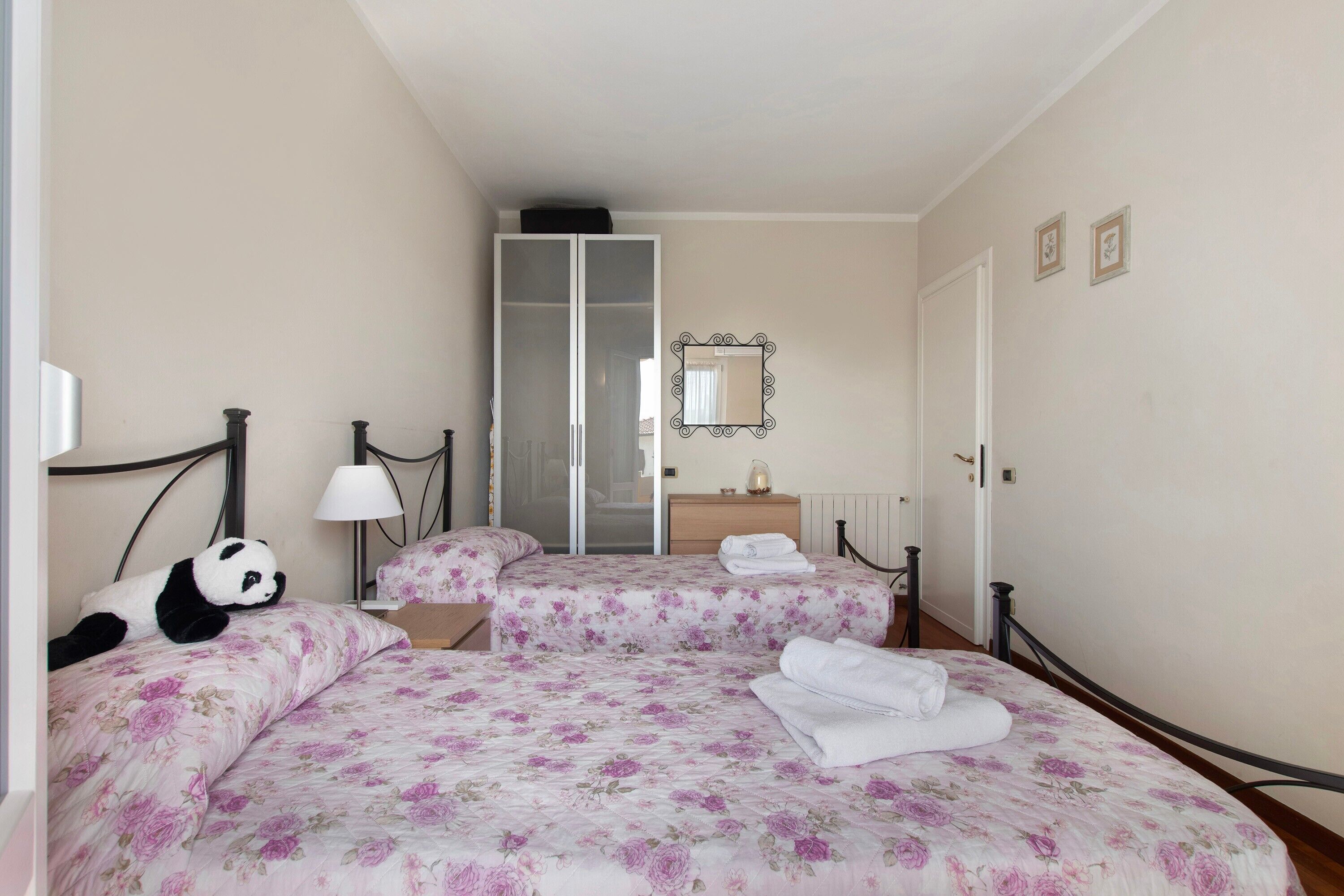 Ein Hotelzimmer mit Bett, Nachttisch, Lampe, Spiegel und Kleiderschrank.