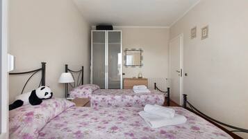 Ein Hotelzimmer mit Bett, Nachttisch, Lampe, Spiegel und Kleiderschrank.