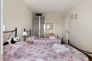 A hotel room with a bed, a nightstand, a lamp, a mirror, and a wardrobe. - Apartment 'Raggio Di Sole' with Balcony and Wi-Fi (Torre del Lago Puccini)