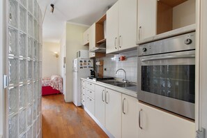 Una cocina compacta con armarios blancos, un horno de acero inoxidable y un microondas.