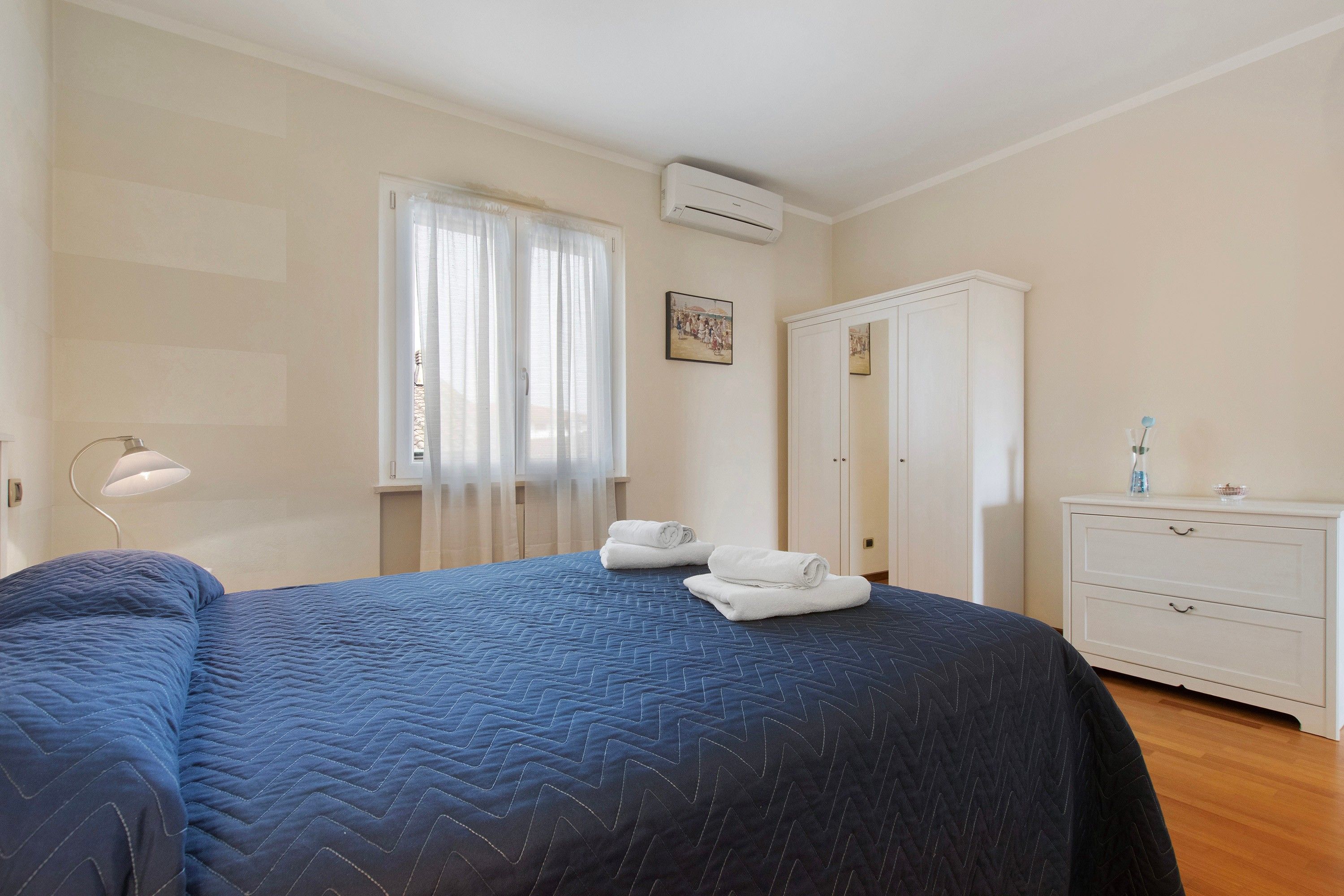Ein Hotelzimmer mit einem Bett, einem Kleiderschrank, einem Schreibtisch und einem Vorhangfenster.