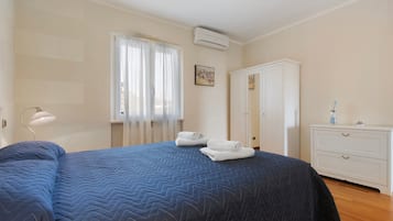 Ein Hotelzimmer mit einem Bett, einem Kleiderschrank, einem Schreibtisch und einem Vorhangfenster.