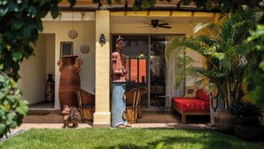 Un patio con un sofá rojo, un jarrón grande y una estatua.