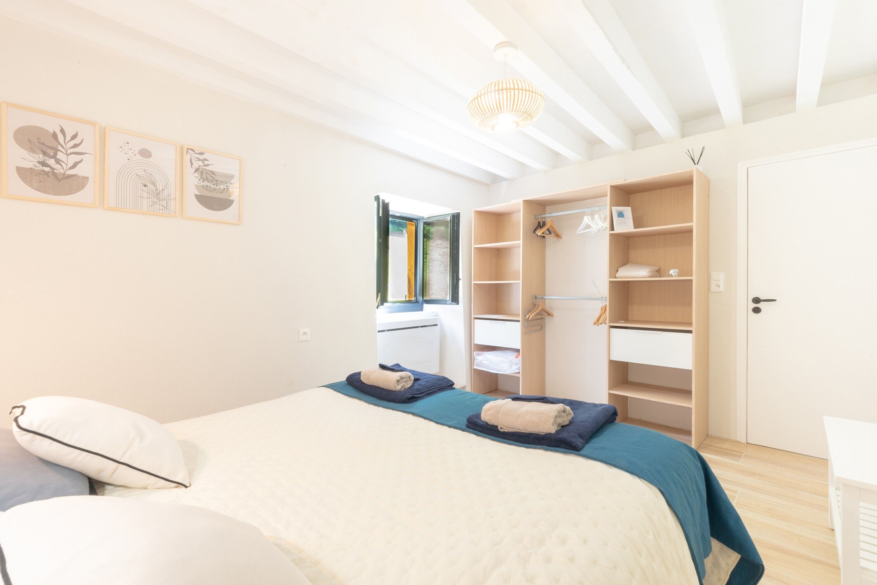 Une chambre à coucher avec un lit, une armoire, une table de chevet et une fenêtre.