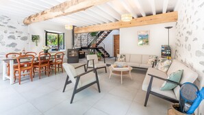 A spacious living area with a dining table, chairs, sofas, and a staircase leading to an upper level. - Holiday Home 'L'authentik' with Mountain View, Private Terrace and Air Conditioning (Accous)