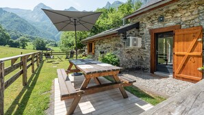 A stone building with a wooden door, a picnic table, and an umbrella. - Holiday Home 'L'authentik' with Mountain View, Private Terrace and Air Conditioning (Accous)