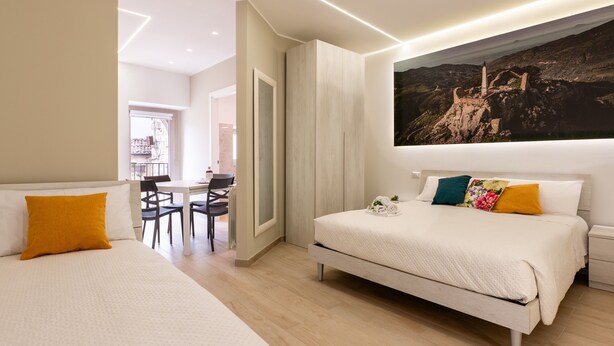 Una habitación de hotel moderna con dos camas, un comedor y un cuadro grande de un paisaje.