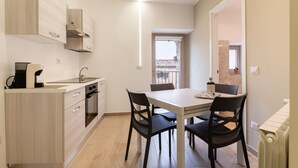 Una cocina moderna con comedor, que cuenta con armarios de madera clara, horno empotrado y una mesa con sillas.