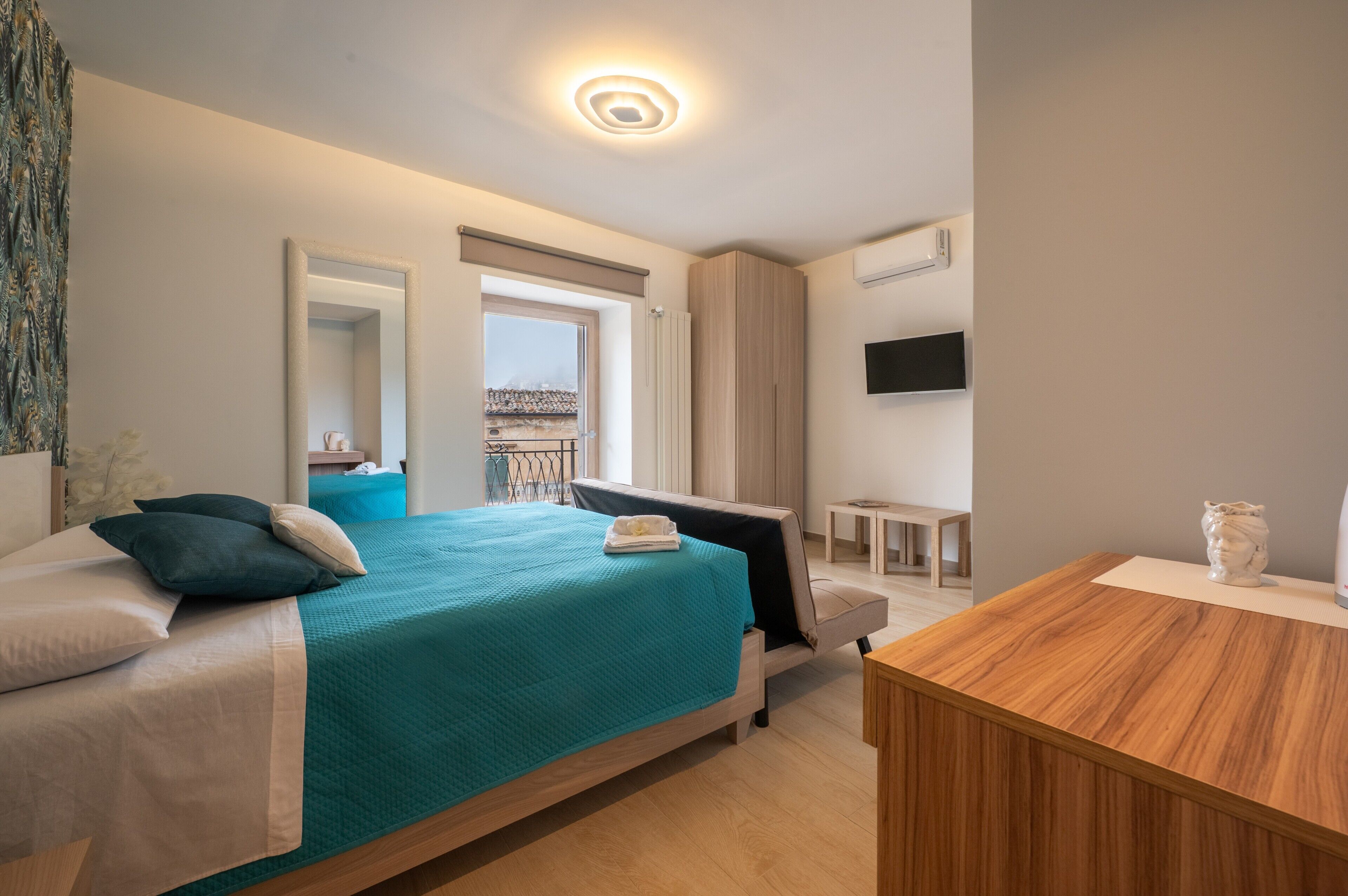 Ein modernes Hotelzimmer mit einem Bett, einem Schreibtisch, einem Stuhl, einem Fernseher und einem Fenster.