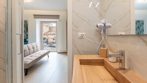A modern bathroom with a marble backsplash, a wooden vanity, a mirror, and a hairdryer.