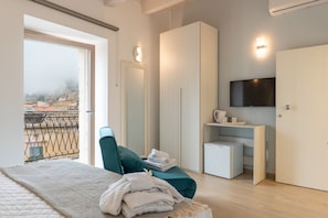 Een moderne slaapkamer met een bed, een stoel, een televisie en uitzicht over de stad.
