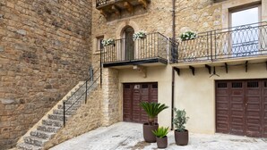 A stone building with a staircase, potted plants, and a balcony with flowers.