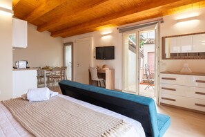 A bedroom with a bed, a desk, a chair, a television, and a sliding glass door leading to an outdoor area. - Studio 5' with Sea View and Private Terrace (Mistretta)