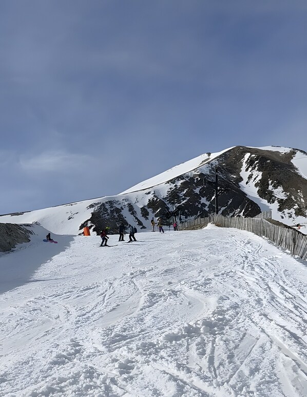 Pendiente nevada de una montaña con una cerca y algunas personas.