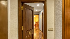 Una puerta de madera que da a un pasillo con una lámpara y un interruptor en la pared.