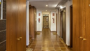 Pasillo de hotel con puertas de madera, suelo de baldosas y equipo de seguridad contra incendios.