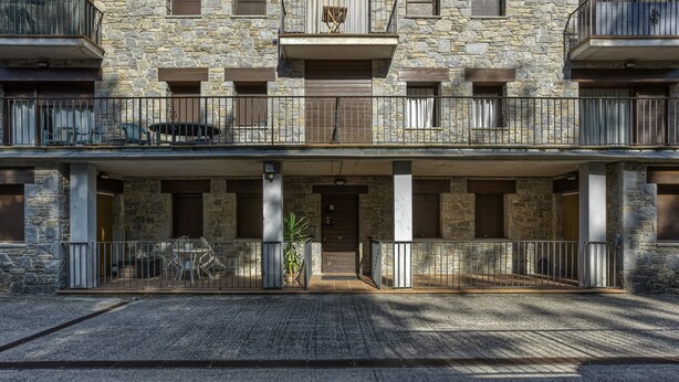 Un edificio de piedra con un balcón, una puerta y una pequeña mesa con sillas.
