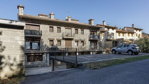 Un edificio residencial de varios pisos con fachadas de piedra, balcones y un área de estacionamiento.