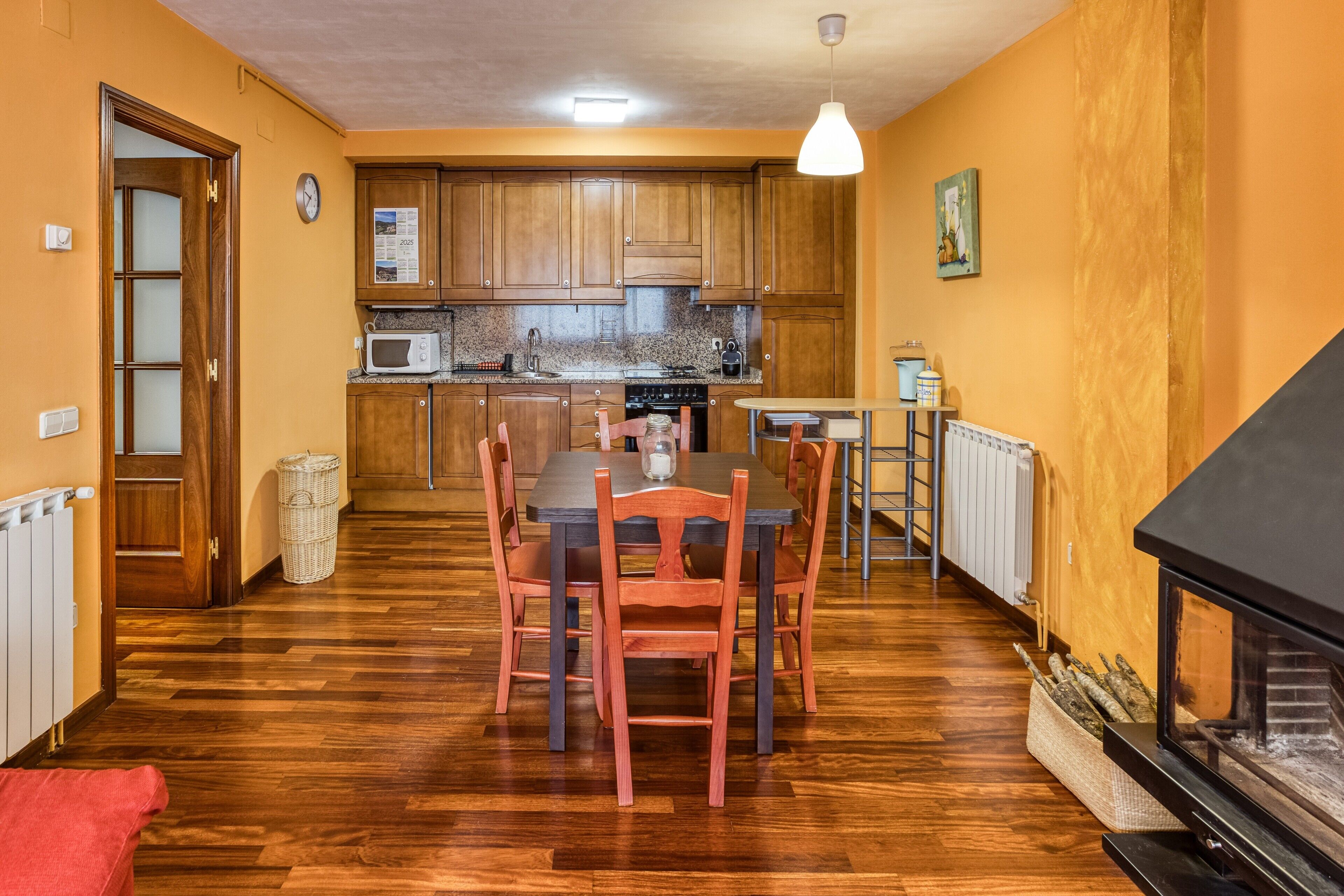 A kitchen with wooden cabinets, a microwave, and a dining table with chairs.