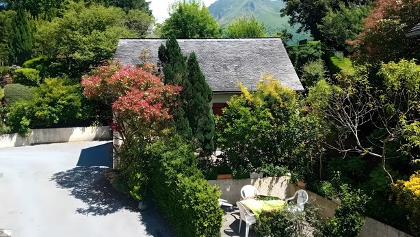 Ein Haus mit einem geneigten Dach, umgeben von üppigem Grün und Bäumen.